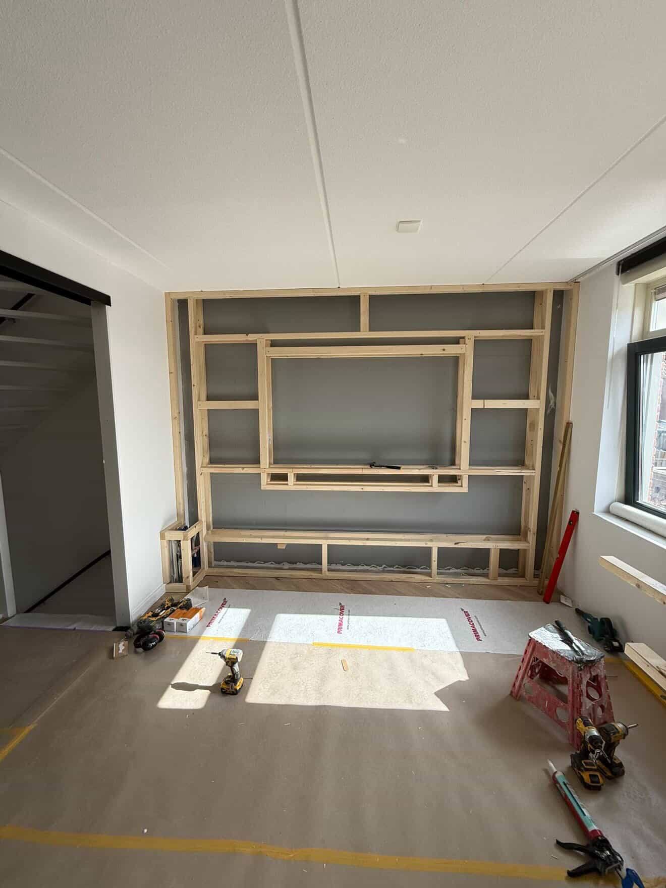 Maatwerk mediawand in opbouw — houten regelwerk, openingen voor tv, haard en nissen