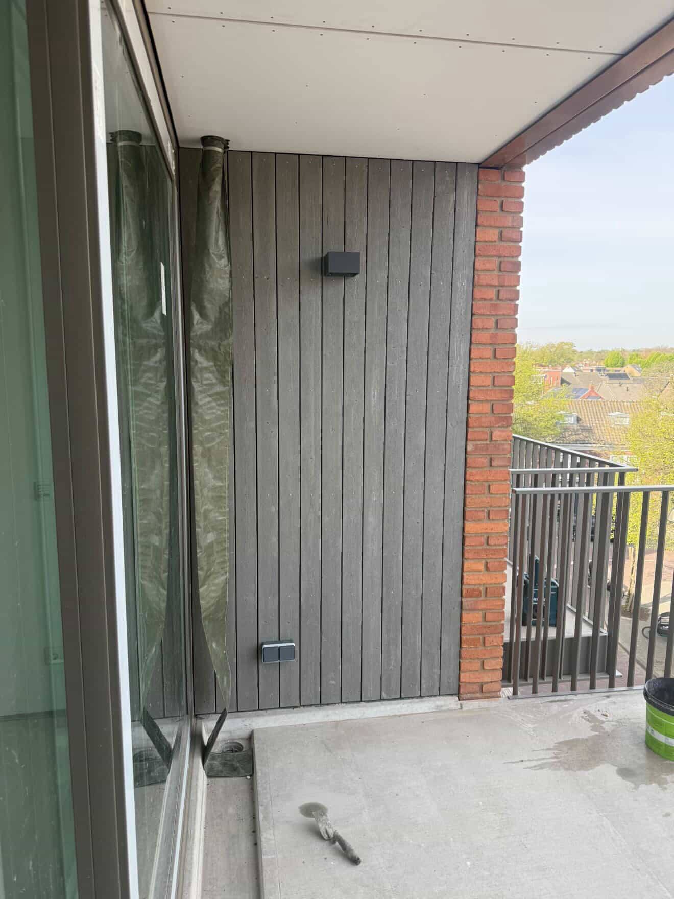 Buitenbekleding — verticaal houten beschot op balkon met metselwerk detail