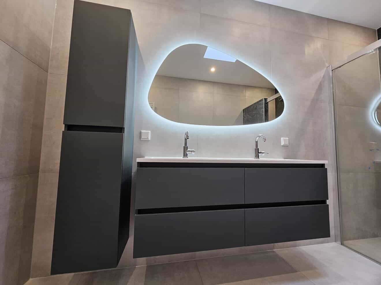 Beton-look badkamer met asymmetrische backlit spiegel en mat zwarte dubbele vanity