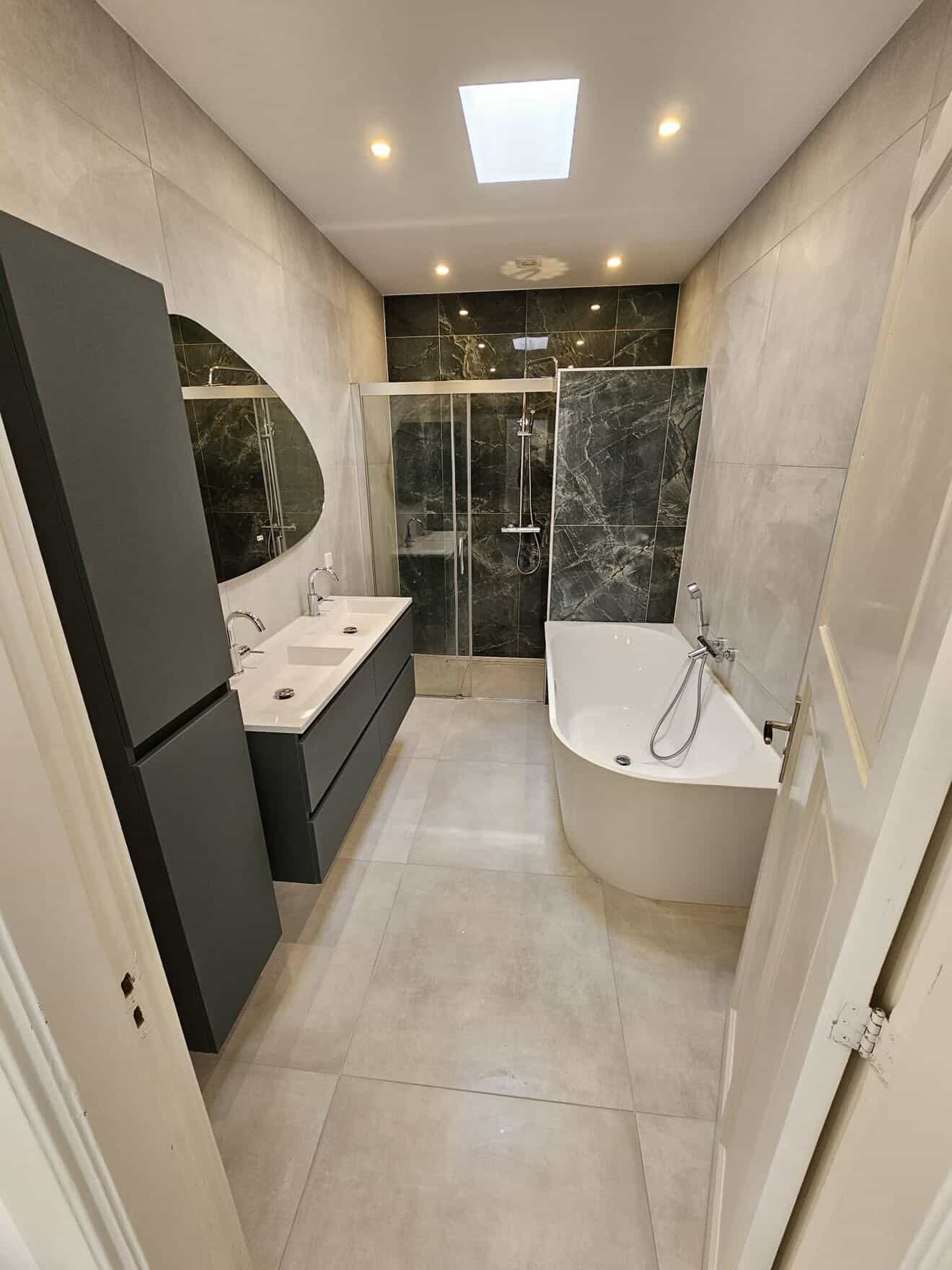 Badkamer met groene marmer douchewand, hoekbad en asymmetrische spiegel